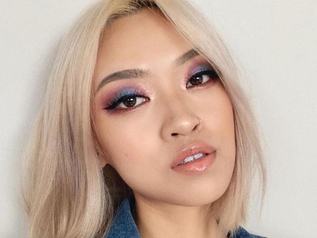 Asian woman with blonde hair and colorful eye makeup