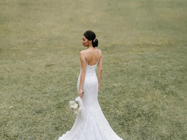 A woman wearing a white backless wedding dress holding a bouquet
