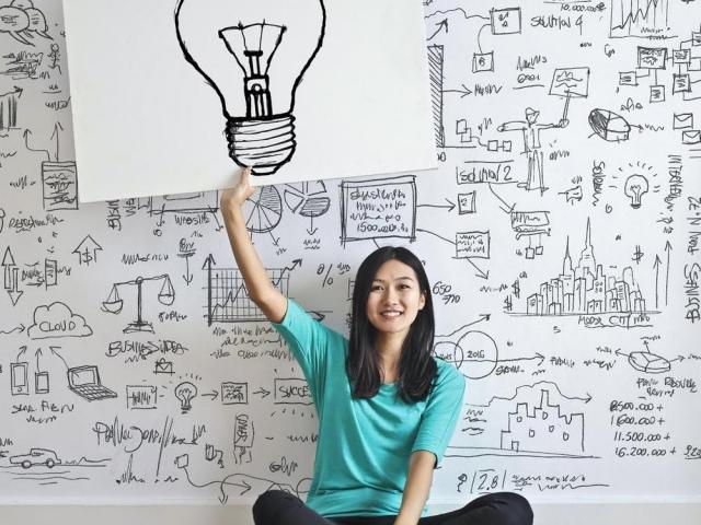 Woman holding a board with a light bulb