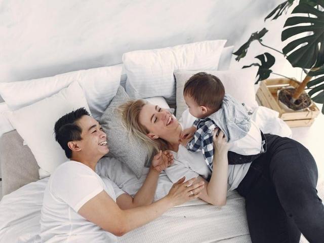 dad and mom playing with baby in bed