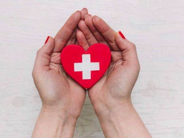 Hands holding a heart with a cross