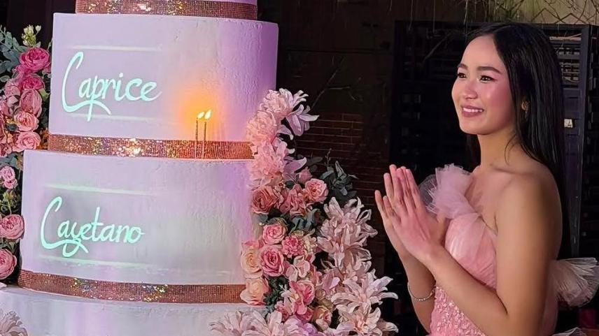 ピンクのドレス姿で、名前入りのケーキを前に笑顔を見せるカプリス・カエタノ