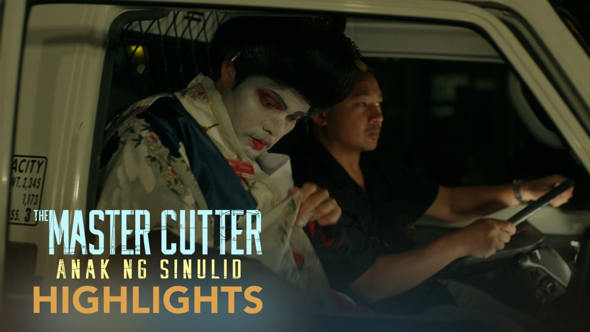車の助手席に身をかがめて隠れるアトイと、運転席の男性。『The Master Cutter』の場面写真。