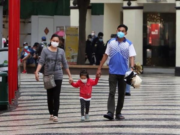 Family walking on the street with face masks on / Photo by: Macau Photo Agency