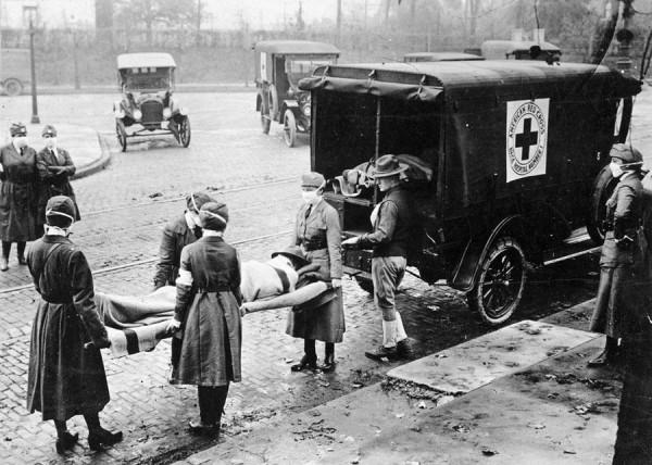 Members of the American Red Cross carrying a victim of the Spanish flu  |  Source: Uncredited photographer for St. Louis Post Dispatch (Wikipedia)